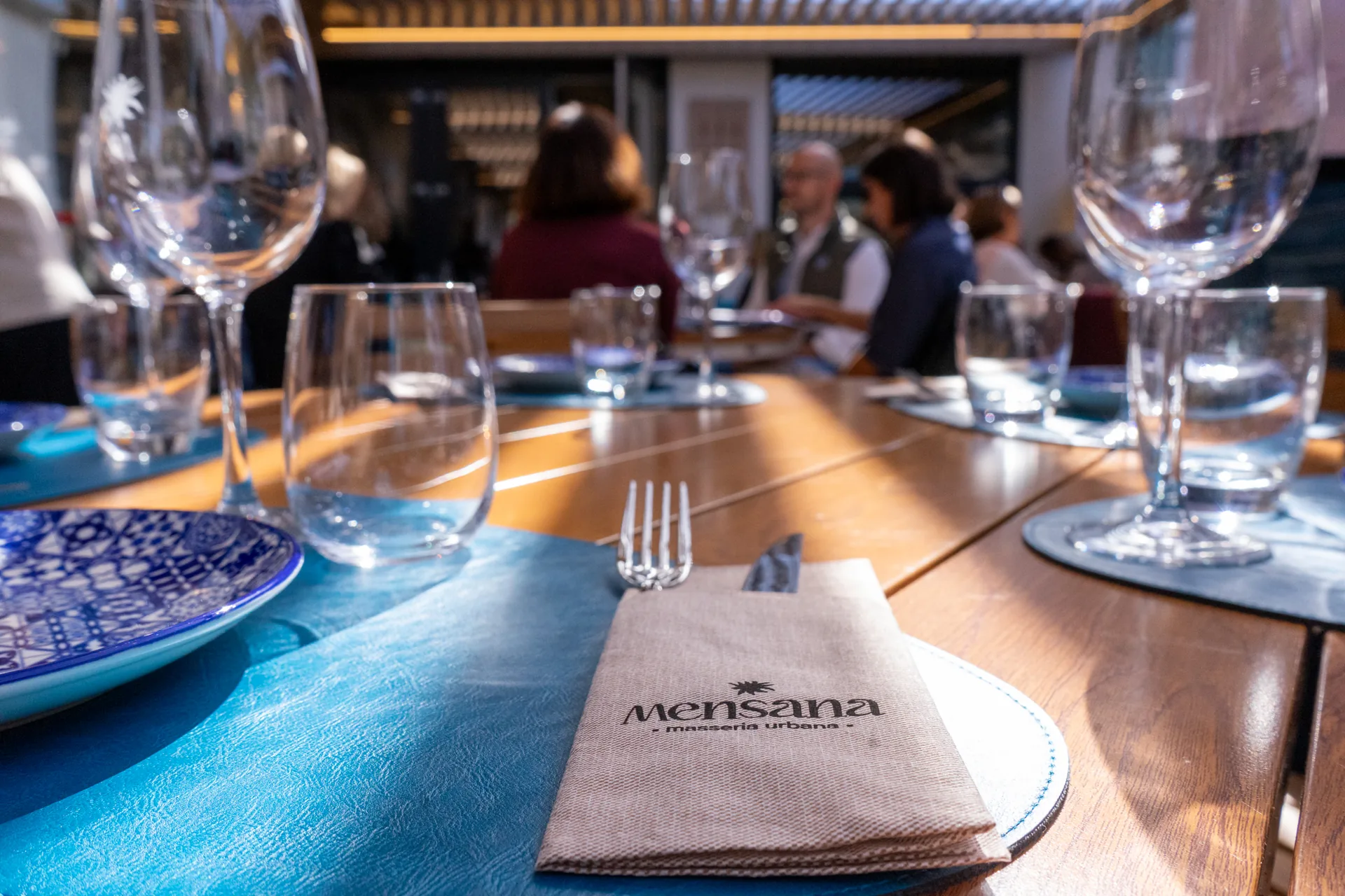 Tavola apparecchiata in sala Mensana, con bicchieri e tovagliolo con il logo